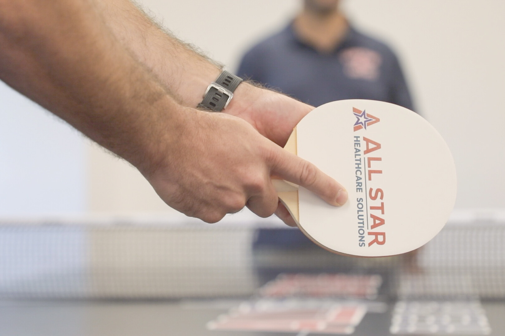Ping Pong focus on paddle with All Star Healthcare Solutions logo