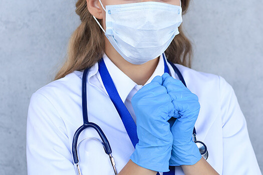 Medical staff preventive gear against coronavirus. Woman doctor in mask with closed eyes praying.