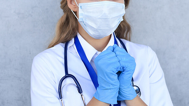 Medical staff preventive gear against coronavirus. Woman doctor in mask with closed eyes praying.