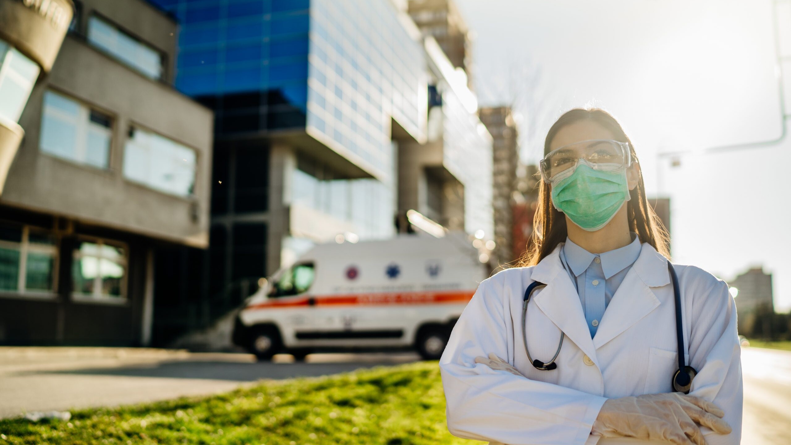 Doctor wearing a mask in front of a hospital