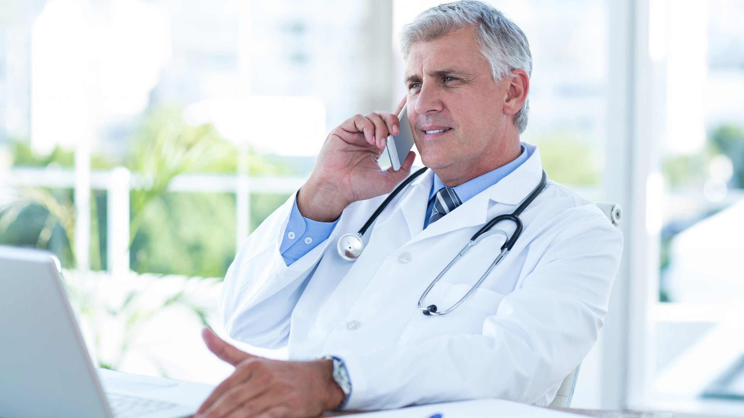 Smiling doctor having phone call at his desk